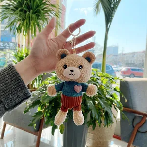 Close-up of a teddy bear keychain in a blue knitted sweater with a pink heart detail