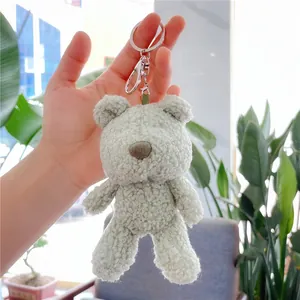 Close-up of a mint green plush teddy bear keychain held in hand with silver metal ring