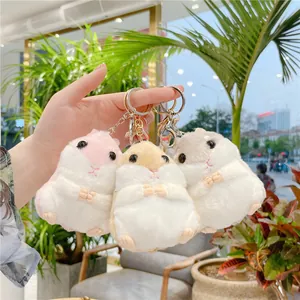 Dettaglio di tre portachiavi a forma di criceto in peluche rosa, beige e grigio