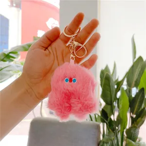 Detailed close-up of a pink plush keychain charm held in hand with golden metal clasp