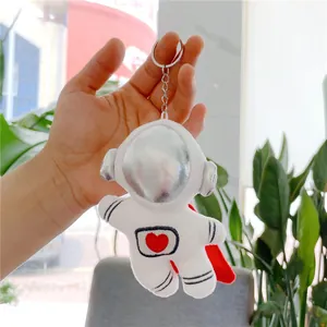 Detailed view of a plush astronaut keychain featuring a red heart and metallic silver visor