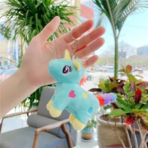 Close-up of a blue plush unicorn keychain held in hand, showing soft texture and rainbow hair
