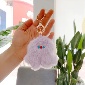 Detailed view of purple plush monster keychain with golden metal ring and lobster clasp