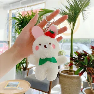 Close-up of fluffy white bunny plush keychain with red cherry decor and green bow