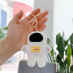 Detailed close-up of plush astronaut pendant with soft white texture and gold metal clasp