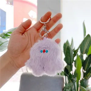 Close-up of a lavender fluffy monster plush keychain with embroidered eyes and metal clip