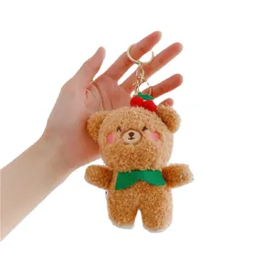 Brown teddy bear plush keychain with red cherry detail and green scarf on white background