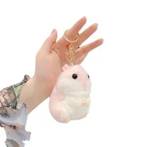 Portachiavi criceto di peluche rosa e bianco con moschettone dorato in mano