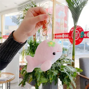 Pink plush whale keychain with gold metal clasp and a small flower accessory