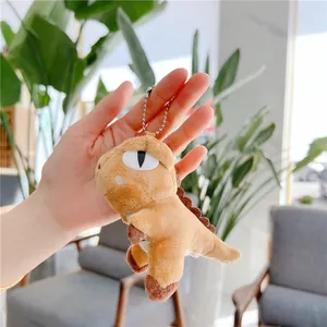 Detailed view of a small light brown plush T-Rex dinosaur keychain with a silver bead chain