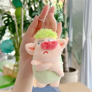 Close-up of a green angry pig plush keychain with cross-arms and a pink nose