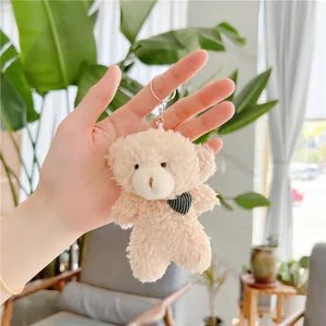 Close-up of a light brown plush teddy bear keychain with black heart charm and silver metal ring