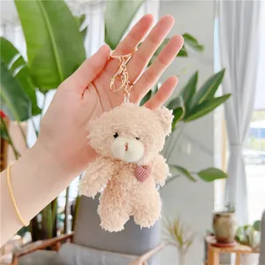 Close-up of a fluffy plush bear charm with a pink heart and golden metal keyring