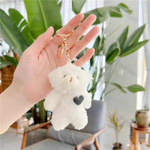 Close-up of white plush bear keychain with black heart embroidery and golden metal ring