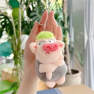 Detail of pink plush pig keychain with green hair and silver metal ring accessory