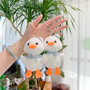 Dettaglio di portachiavi a forma di anatra in peluche con sciarpa blu e ganci