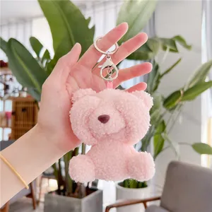 Detailed view of a soft pink teddy bear plush keychain with a metal clasp and ribbon