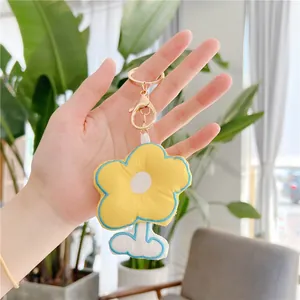 Close-up of plush flower keychain with yellow petals and gold metal lobster clasp