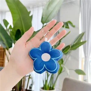 Macro shot of blue plush flower keychain with silver bead chain and white loop detail