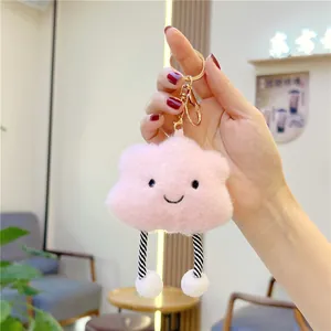 Detailed close-up of a pink plush cloud keychain with embroidered face and stripe legs