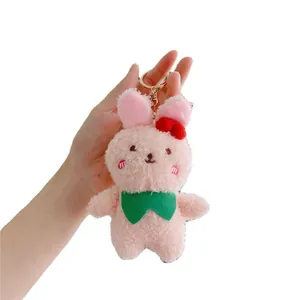 Pink plush rabbit keychain with red polka dot bow and golden ring held in hand