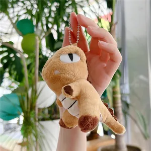 Close-up of a small plush dinosaur keychain in brown with soft fabric and silver bead chain