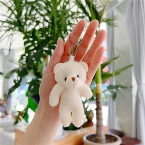 Λούτρινο αρκουδάκι μπρελόκ σε κρεμ χρώμα με ασημί αλυσίδα σε κοντινό πλάνο χεριού