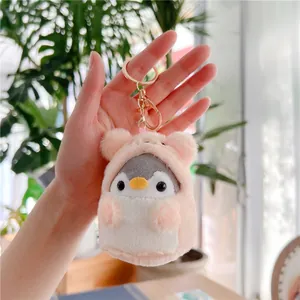 Close-up of cute plush penguin keychain with pink hoodie and golden lobster clasp detail