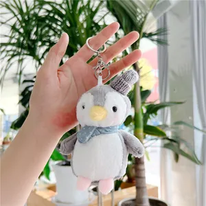 Close-up of plush penguin keychain with blue polka dot scarf and silver metal clasp