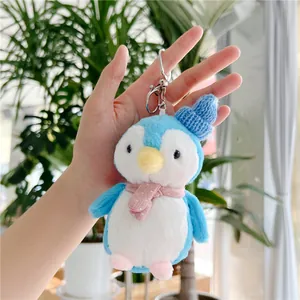 Close-up of blue plush penguin keychain with pink polka dot scarf and blue knitted hat