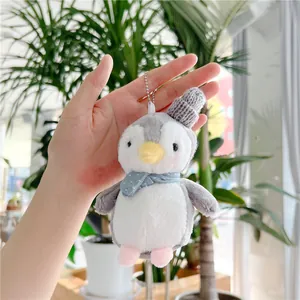 Close-up of cute plush penguin pendant with a grey knit hat and blue polka dot scarf