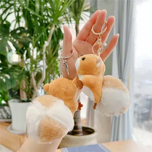 Detailed view of plush squirrel keychains with golden hardware held against greenery