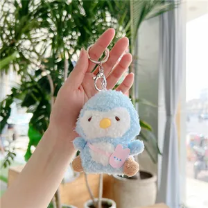 Close-up of blue plush penguin keychain with pink rabbit bag in a natural setting