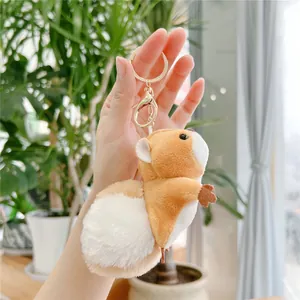 Close-up of cute plush squirrel keychain with golden metal clasp held by hand