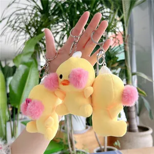 Three plush yellow duck keychains with pink cheeks and metal rings in a natural setting