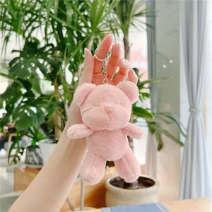 Detailed shot of a fluffy pink teddy bear plush keychain with a silver metal ring link