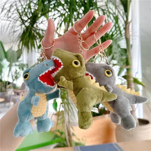 Three colorful candy plush dinosaur keychains in blue, green, and grey with gold hooks