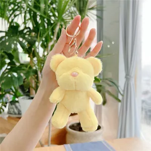 Detail of yellow plush teddy bear keychain with soft fur and golden metal lobster clasp