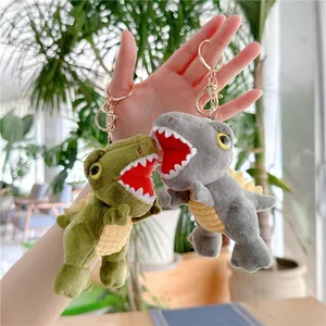 Close-up of soft plush dinosaur keychain with golden metal clasp in green and grey colors