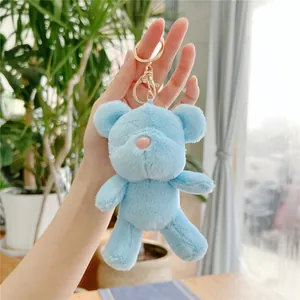 Close-up of a light blue plush teddy bear keychain with a golden metal clasp and soft fur