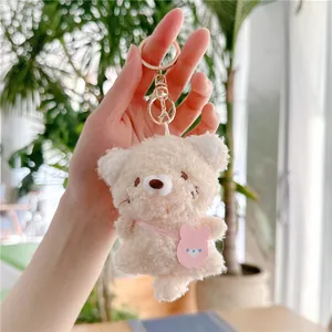 Detail van witte pluche beer sleutelhanger met roze konijnentasje en gouden sluiting