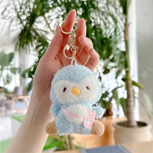 Detail van blauwe pluche pinguïn sleutelhanger met roze konijnentas en gouden gesp