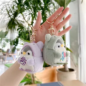 Cute penguin plush keychain set with animal hoods and ice cream accessories held by hand
