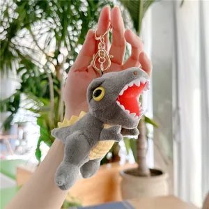 Close-up of a grey dinosaur plush keychain featuring yellow fins and sharp white teeth