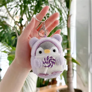 Detail of penguin plush keychain wearing a purple bear hoodie holding a lollipop