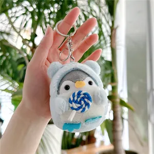 Close-up of plush penguin keychain wearing light blue hoodie holding a lollipop