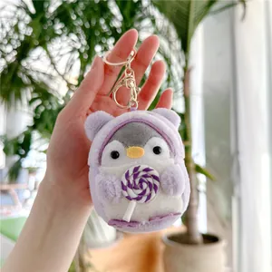 Close-up of penguin plush keychain wearing purple hoodie and holding a swirl lollipop