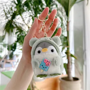 Detail of plush penguin keychain wearing a green frog hoodie holding a blue ice cream