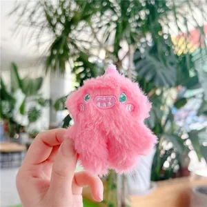 Close-up of a pink plush monster keychain with fluffy texture and embroidered cartoon face