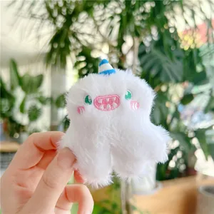Detailed embroidery view of a fluffy white monster plush keychain with striped blue horn